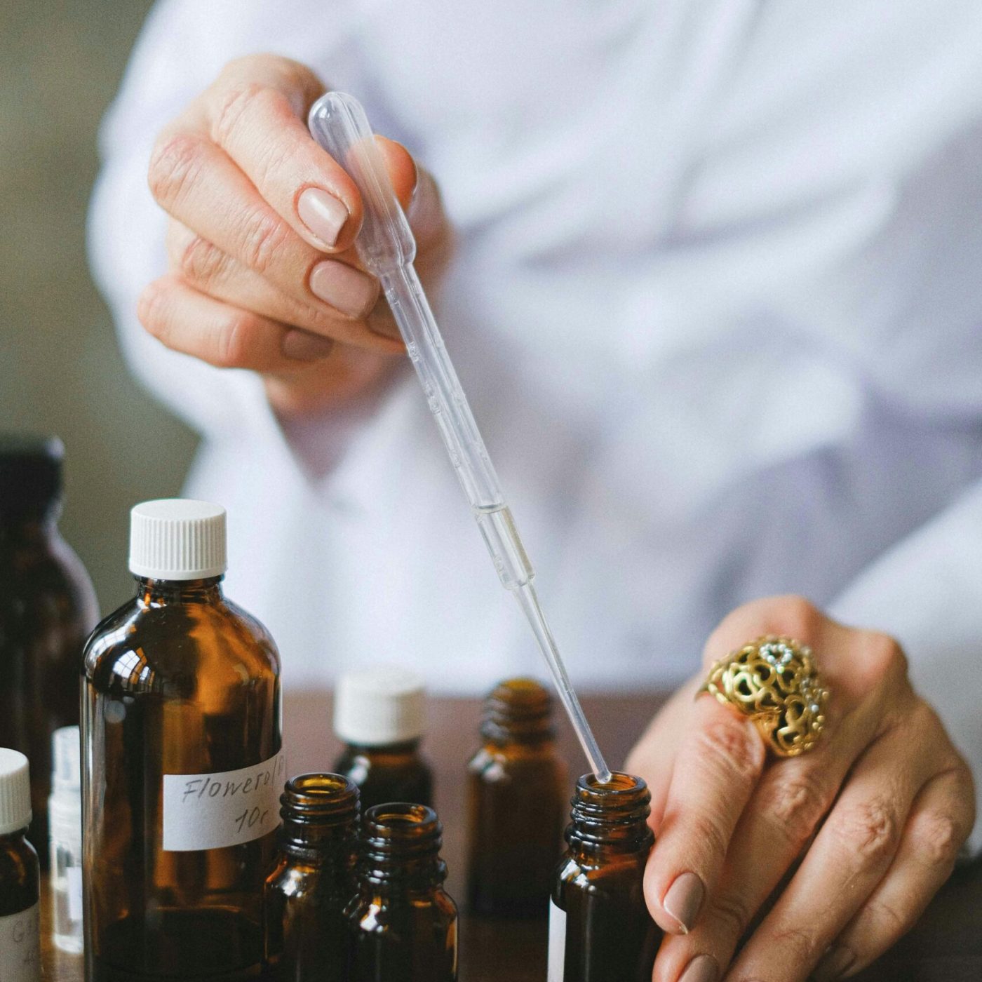 Close-up of a person using a dropper with essential oil bottles, showcasing aromatherapy setup.