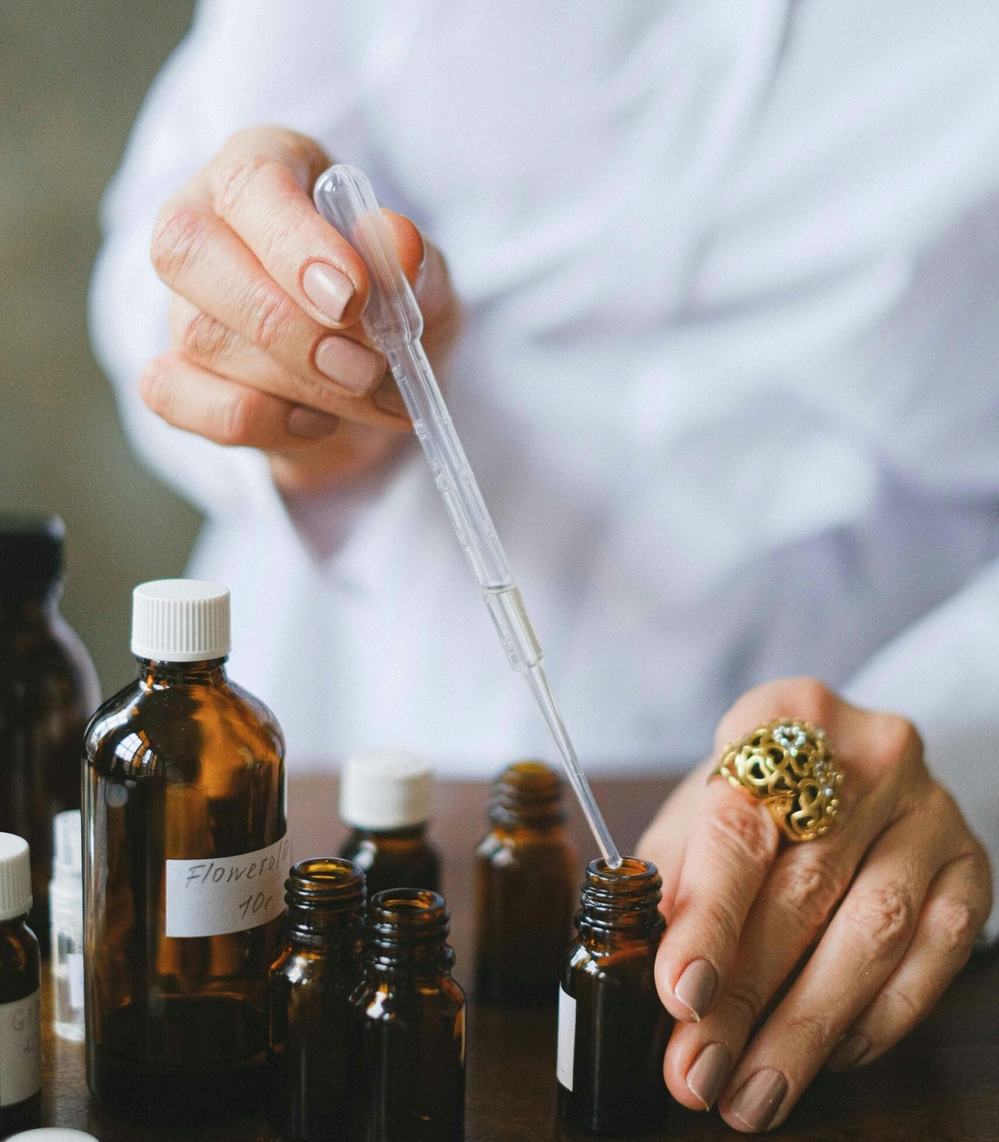 Close-up of a person using a dropper with essential oil bottles, showcasing aromatherapy setup.